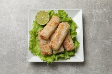 Delicious fried spring rolls on grey table, top view