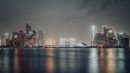Modern City Skyline at Night with Water Reflection
