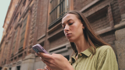 Close-up of a young woman using a mobile phone on the street of a European city