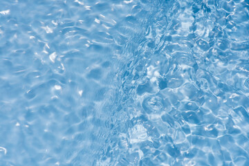 Bluewater waves on the surface ripples blurred. Defocus blurred transparent blue colored clear calm water surface texture with splash and bubbles. Water waves with shining pattern texture background.