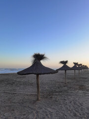 Beach umbrellas against the setting sun of the Atlantic coast of Argentina, Buenos Aires province, Mar Azul