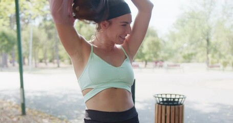 A focused woman in a park changes her shirt post exercise, showcasing an active lifestyle and the concept of fitness outdoors.
