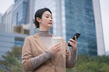 Professional Woman with Smartphone and Coffee Downtown