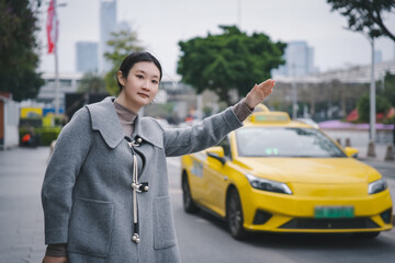 Young Woman Hailing a Taxi on Urban Street