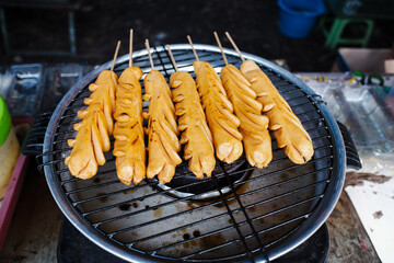 Several red sausages are being grilled in the oven.