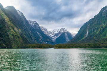 Fototapeta na wymiar Photograph of mountains in clouds and mist viewed from the water in Milford Sound in Fiordland National Park on the South Island of New Zealand