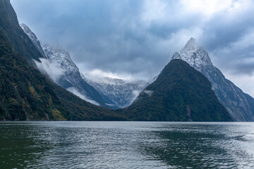 Photograph of mountains in clouds and mist viewed from the water in Milford Sound in Fiordland National Park on the South Island of New Zealand