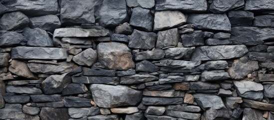 A detailed closeup of a grey stone wall built with large bedrock rocks, showcasing the intricate pattern of the brickwork and the sturdy building material