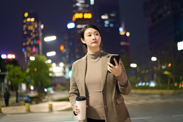 Businesswoman with Smartphone Walking at Night