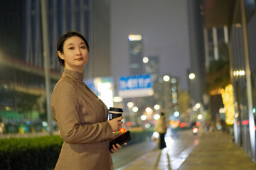 Confident Businesswoman with Coffee on City Night Background