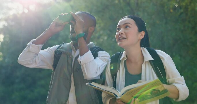 Adventure, people and bird watching in a forest with book, journey and view with backpack. Binoculars, nature and outdoor in a rainforest with trekking, walk and animal textbook with search in jungle