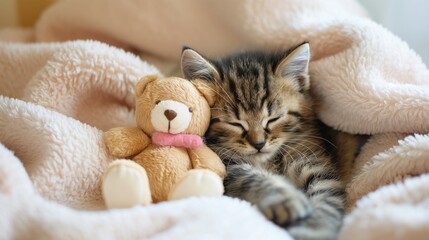 A sleepy baby kitten sitting against a plush toy in a comfortable bed