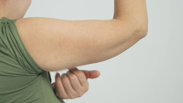  Woman checking her upper arm and excess fat