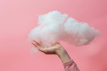 a womans hand is holding a cloud against pink background