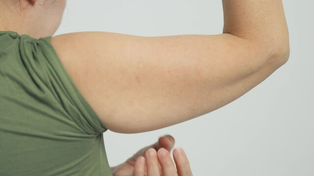  Woman checking her upper arm and excess fat