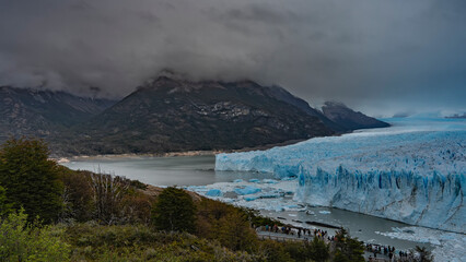 People admire the Perito Moreno glacier from the observation deck. A mass of blue ice with cracks,...