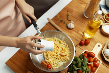 Close up of hand chef influencer cooking spaghetti mix ingredient taking to frying pan, putting...