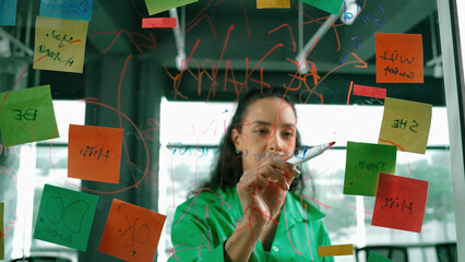 Portrait of smart professional hispanic businesswoman writes marketing ideas on glass board with...