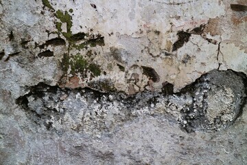 texture of a wall with destroyed bricks, crumbling plaster and damaged protective paint, abstract background. Brick wall with crumbling plaster.