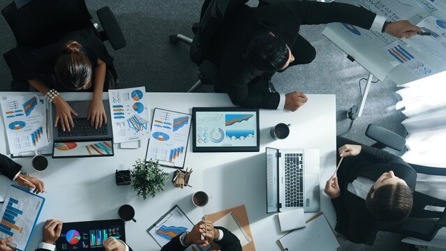 Top view of smart business people brainstorm marketing idea at meeting table while compare stock market investment data between laptop and tablet. Business team planning financial plan. Directorate.