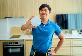 Technician installing fire safety detector in a modern apartment - obrazy, fototapety, plakaty