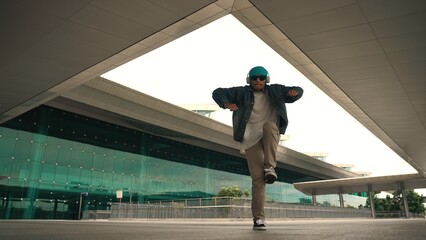 Motion shot of happy hipster practice b boy dance with stylish cloth at building. Dancer enjoy show...