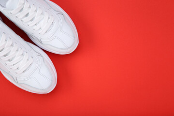 Pair of white shoes on red background
