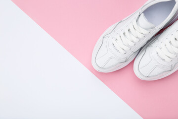 Pair of white shoes on white and pink background