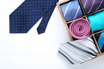 Colored neckties in basket on white wooden table