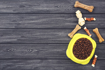 Dry pet food in bowl with bones on black wooden table - 760327529