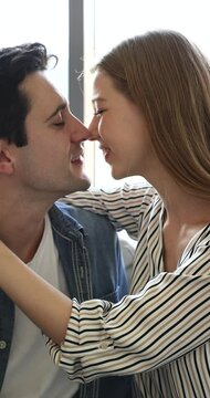 Pretty Hispanic loving woman caressing, touching her smiling handsome boyfriend indoor. Beautiful millennial affectionate couple kissing, enjoy time together and their first real love. Relations, date