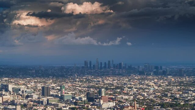 City of Los Angeles cityscape changing from gloomy rainy weather to a sunny sunset as dramatic storm clouds pass above downtown LA skyline. Timelapse, 4K UHD.