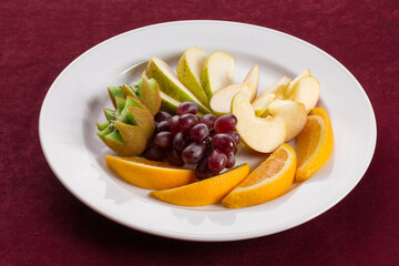 A plate of tropical fruits standing on red velvet