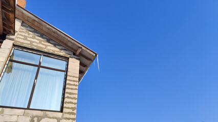 Sharp icicles from melted snow hanging from eaves of roof. Beautiful transparent icicles. Icicles on the eaves of the house
