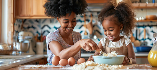 Smiling African American mother helping daughter mix eggs for dough in kitchen