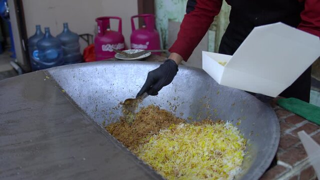 Chef preparing biryani rice with lamb meat from a large wok. Delicious middle eastern food.