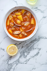 Bowl of manhattan clam chowder on a white marble background, vertical shot with space, top view