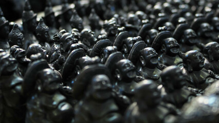 Many black colored Buddha statue made from carved stone in souvenir store at Phuket, Thailand. Sculptures and carvings for home table decoration