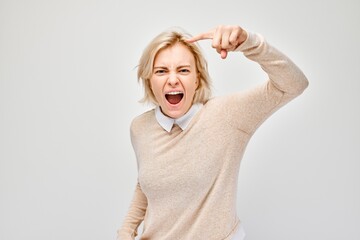 Portrait of angry blond woman points her finger at the camera and yells on white background - obrazy, fototapety, plakaty