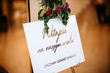 Sala weselna i powitanie pary młodej. Wesele i tablica powitalna dla gości. Witajcie napis na sali weselnej. Goście weselni. Wesele w Polsce © jusiamastalerz