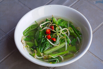 Home made food green mustard vegetables or tumis sayur sawi served in white bowl on the table