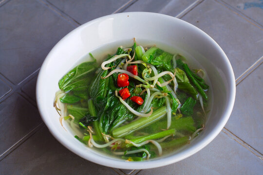 Home made food green mustard vegetables or tumis sayur sawi served in white bowl on the table