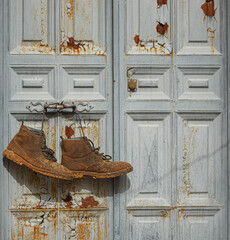 Puerta vieja con unas botas colgadas llenas de barro 