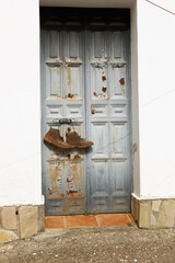 Puerta vieja con unas botas colgadas llenas de barro 
