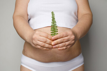 young adult human stomach tummy and green leaf in female hand closeup. Healthy eating, diet,...