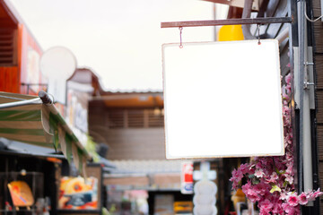 Blank vintage sign board hanging on pole at small old restaurant in the market.