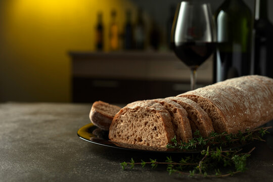 Freshly cut bread with red wine on a kitchen table.