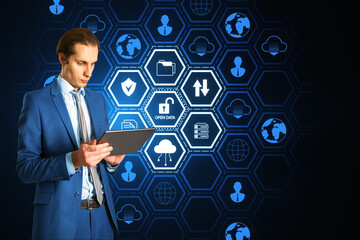 Attractive young european businessman using tablet with creative open data hexagonal hologram on...