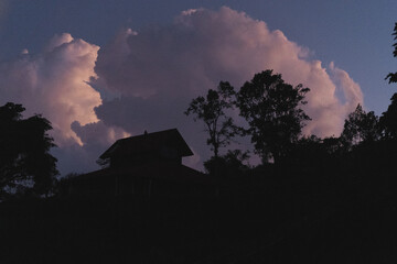 Fototapeta na wymiar Sunset in the Bedugul jungle, blue sky, clouds, house on the mountain.