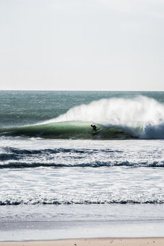person surfing a wave, breaking on the shore, high contrast